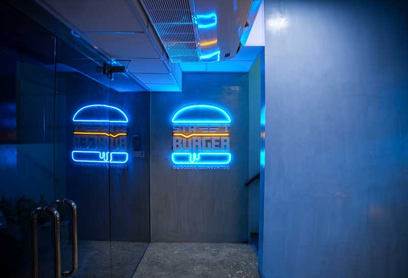 Vibrant neon sign of Street Burger illuminating the Nawala store entrance, inviting customers with its lively glow.